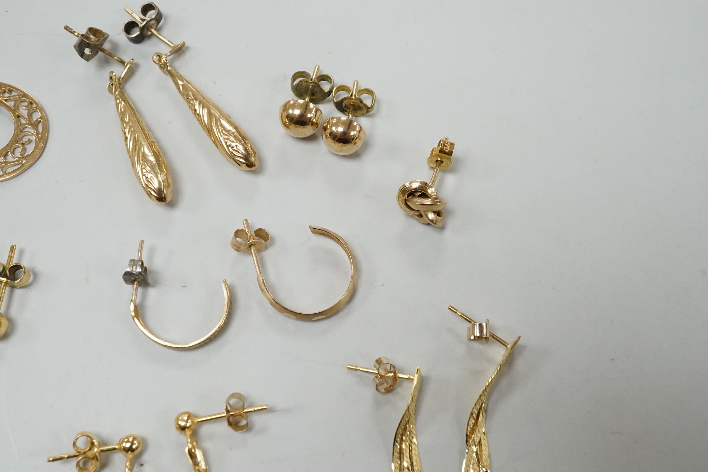 Seven assorted modern pairs of 9ct earrings including tassel drop and pear shaped, 12.7 grams and ten other yellow metal pairs, three odd ear studs and a small heart pendant?